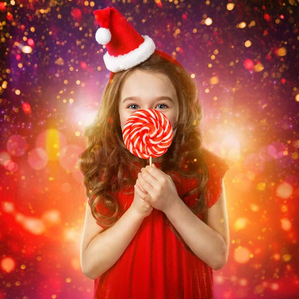 Bambina col cappello da Babbo Natale con bastoncino di zucchero. Tempo di Natale — Foto Stock