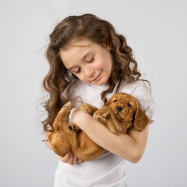 Beyaz arka plan üzerinde izole köpek yavrusu olan küçük kız. Çocuk evde beslenen hayvan dostluk
