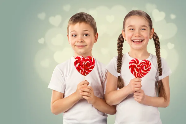 Мальчик и девочка с конфетно-красным леденцом в форме сердца. Портрет ко Дню Святого Валентина . — стоковое фото