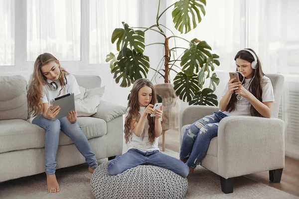 Skupina dospívajících dívek je používání miniaplikací. Děti s telefony a tablety, smartphony a sluchátka — Stock fotografie
