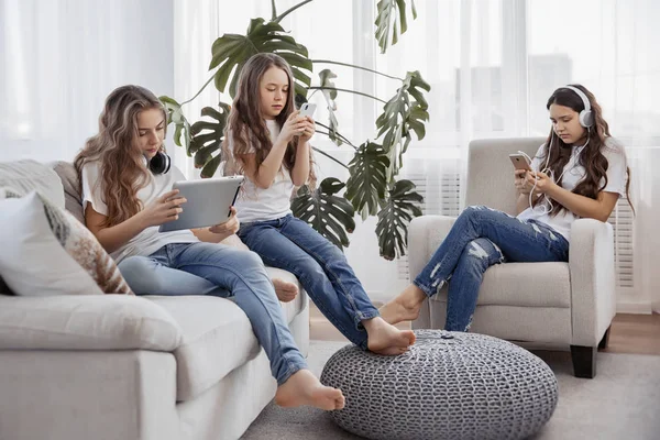 Barn med telefoner och surfplattor, smartphones och hörlurar. Grupp av tonårsflickor använder prylar. — Stockfoto