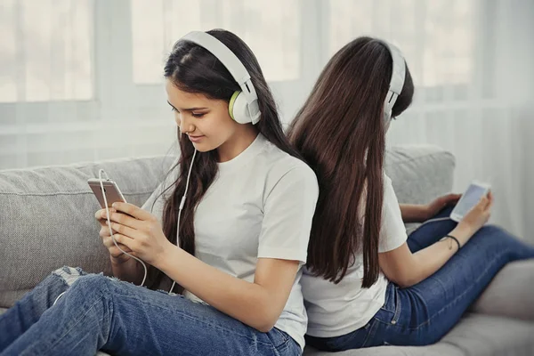 Έφηβες αδελφές με έξυπνο τηλέφωνο και τα ακουστικά, ακούγοντας μουσική και ommunicate σε κοινωνικά δίκτυα — Φωτογραφία Αρχείου