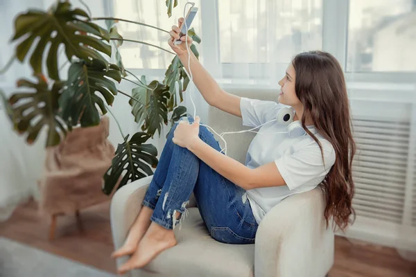 Hermosa adolescente con teléfono inteligente está haciendo una selfie . — Foto de Stock