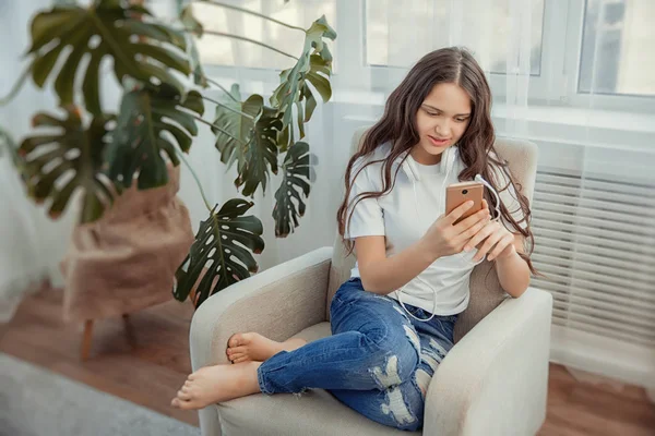 Hermosa adolescente con teléfono inteligente y auriculares escuchando música . — Foto de Stock