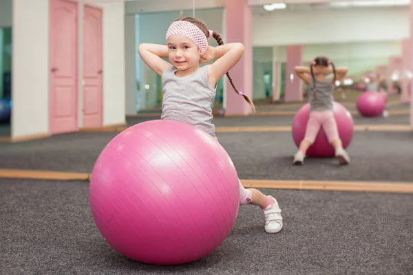 Девочка делает фитнес-упражнения на фитнес-мяч в оздоровительном клубе, растягивается в упражнениях . — стоковое фото