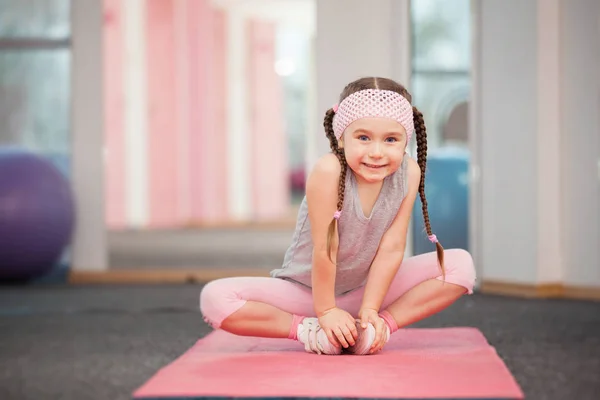 Girl child doing fitness exercises in health club, stretching in exercise — Stock Image Girl child doing fitness exercises in health club, stretching in exercise Stock Photo
