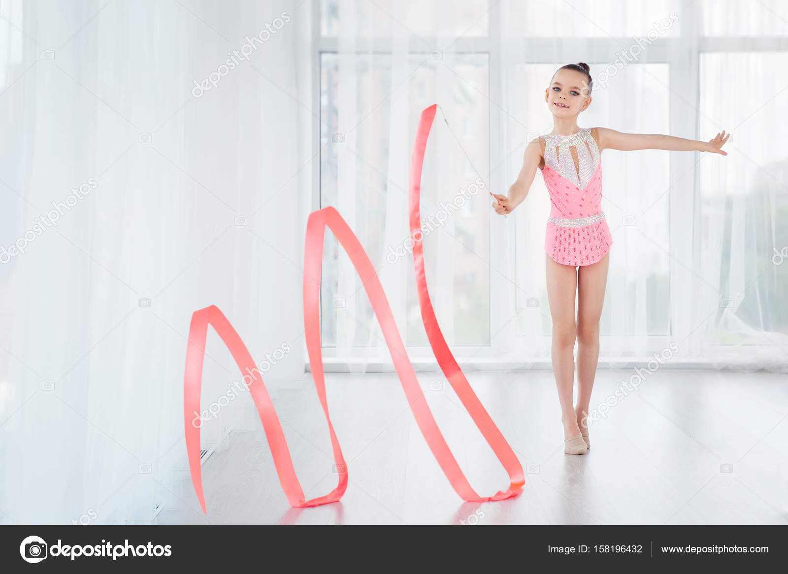 Hermosa niña gimnasta en vestido deportivo rosa, haciendo ejercicio de gimnasia  rítmica Espirales con cinta de arte: fotografía de stock © SvetaOrlova  #158196432
