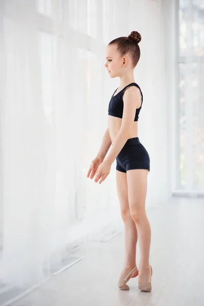 Schöne kleine fitte Turnerin, die Gymnastikübungen macht oder im Fitnesskurs trainiert — Stockfoto