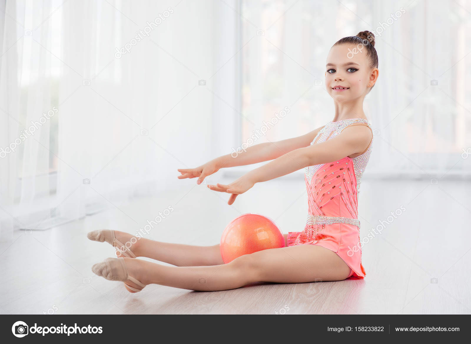 Hermosa ni a gimnasta en vestido de ropa deportiva rosa la