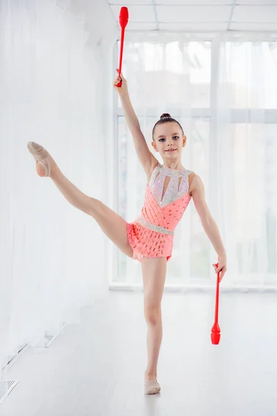 Vacker liten gymnast flicka i rosa sportkläder klänning, utför konst gymnastik element med mace i fitness klass — Stockfoto