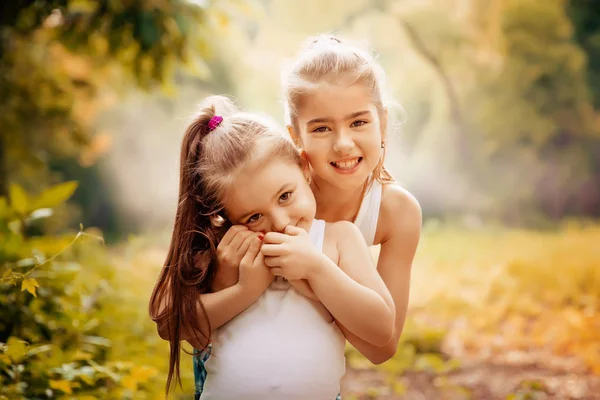 Παιδική ηλικία, οικογένεια, φιλία και έννοια άτομα - δύο ευτυχής παιδιά αδελφές αγκαλιάζει σε εξωτερικούς χώρους. — Φωτογραφία Αρχείου