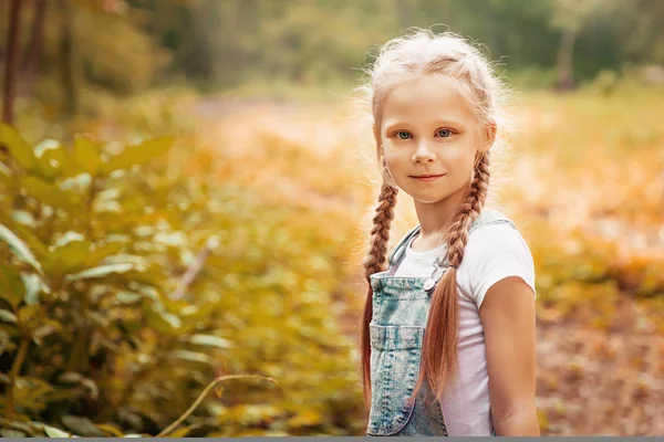 Bedårande leende liten blond flicka med flätor. Söta barn ha roligt på en solig sommardag utomhus. — Stockfoto