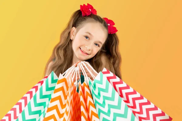 Venda. Menina bonito com muitos sacos de compras. Retrato de uma criança em compras . — Fotografia de Stock