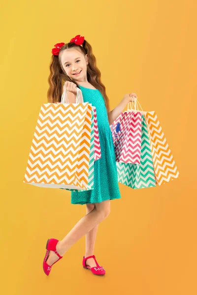 Venda. Menina bonito com muitos sacos de compras. Retrato de uma criança em compras . — Fotografia de Stock