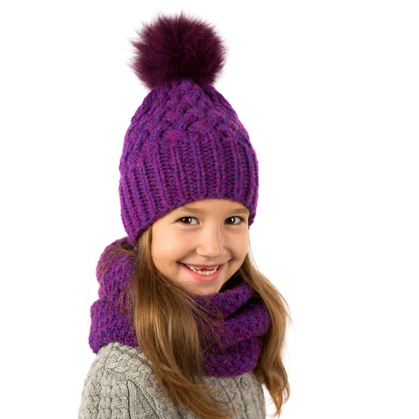 Девочка в зимней теплой фиолетовой шапке и шарфе на белом. Детская зимняя одежда — стоковое фото