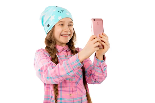 A sweet girl holds a smart phone in her hands and smiles. Isolated on a white background. — Stock Photo, Image