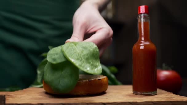 Chef voegt blaadjes van de spinazie toe aan de hamburger — Stockvideo