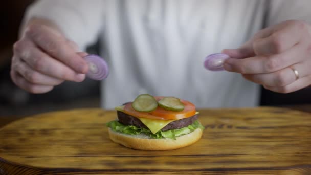 Chef-kok kookt hamburger en zet ringen van rode ui — Stockvideo