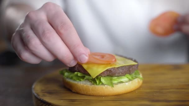 Chef cocina hamburguesa y pone tomate fresco en rodajas — Vídeos de Stock