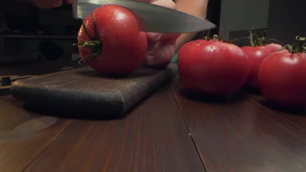 Chef corta tomate rojo maduro por la mitad en la madera — Vídeos de Stock