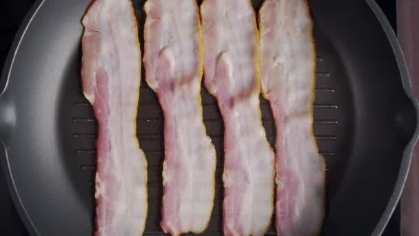 Flat lay shot of pieces of bacon being roasted on the hot grill pan — Stock Video