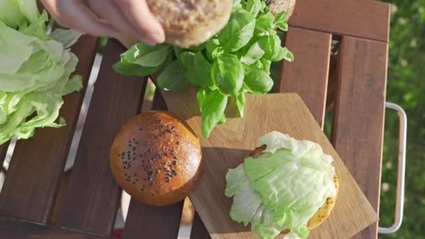 Der Koch legt Schnitzel aufs Brötchen und macht Burger — Stockvideo
