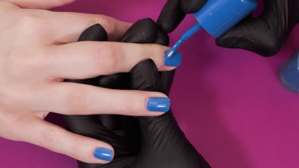マニキュリストは顧客の爪を青の色合いで描きます — ストック動画
