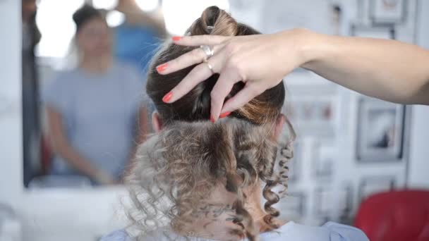 스타일리스트는 뜨거운 곱슬머리를 사용하여 여자용으로 머리를 곱슬곱슬 하게 하는 스타일 — 비디오