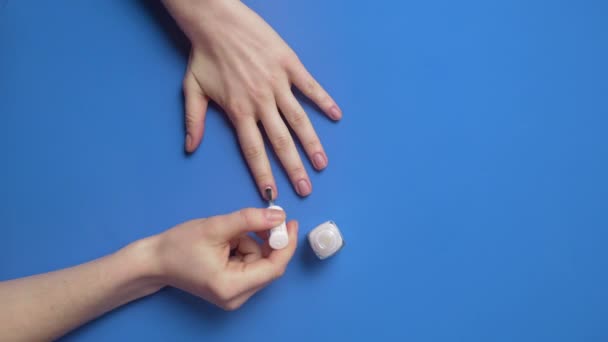 Женщина красит ногти прозрачным защитным ногтем — стоковое видео