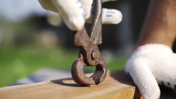Человек в рабочих перчатках вытаскивает забитый гвоздь — стоковое видео