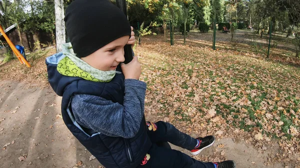 Çocuk parkta salıncakta sallanırken eğleniyor.