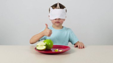 Maskeli küçük çocuk yeşil elmayı denedi ve onayladı.