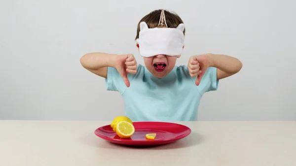 Maskeli küçük çocuk limonu dener ve tahmin eder.
