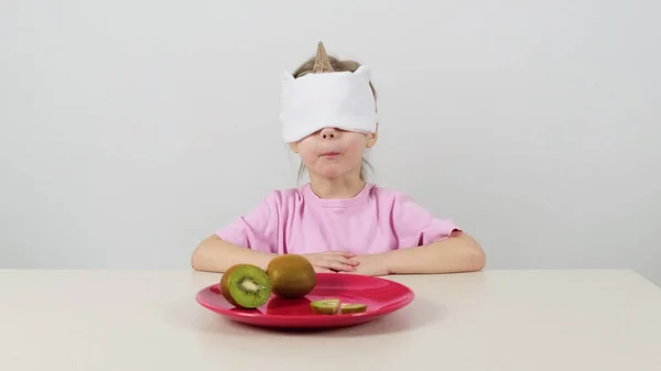 Kleines Mädchen Maske Versucht Grüne Kiwi Erraten lizenzfreie Stockbilder