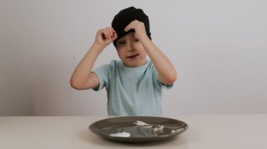 Siyah maskeli bir çocuk çeşitli yiyecekler denedi ve tahmin etti ve onayladı.