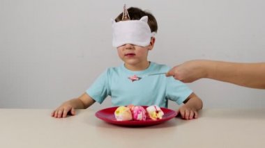 Maskeli küçük çocuk dondurma yemeye çalışıyor ve tahmin ediyor.