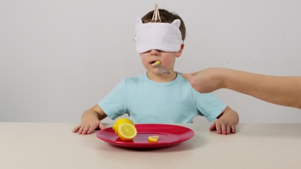 戴面具的小男孩试图用猜的方法猜柠檬 — 图库视频影像