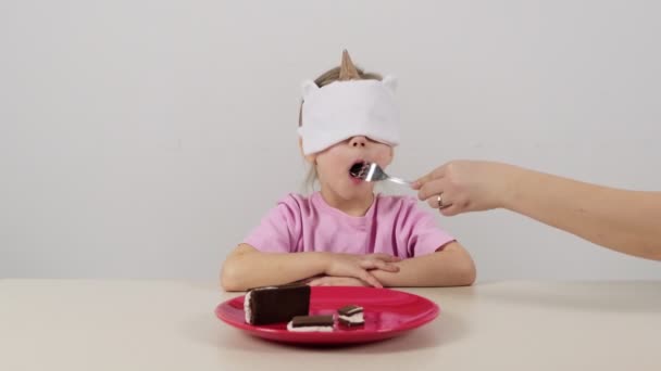 戴面具的小女孩试图用白奶油猜巧克力蛋糕 — 图库视频影像