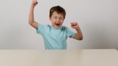 Masadaki küçük çocuk ayağa fırlar ve zaferle sevinir. Yavaş çekim