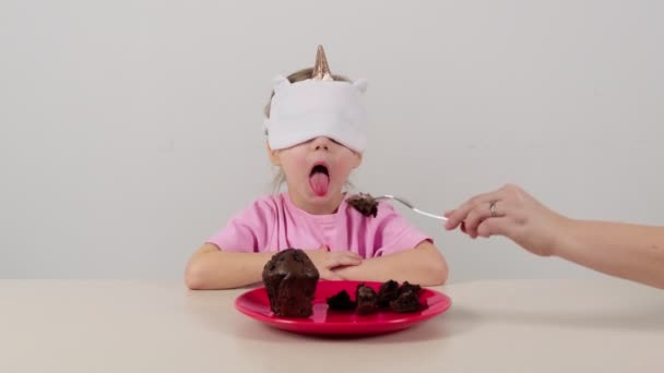 戴面具的小女孩试着猜巧克力松饼 — 图库视频影像