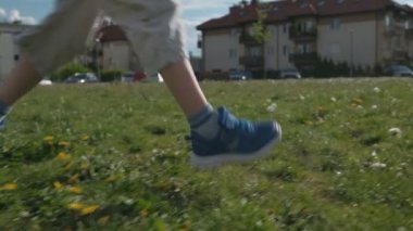 Futbol oynayan bir çocuk. Elinde futbol topu olan çocuk yeşil çimlerin arasında koşuyor.
