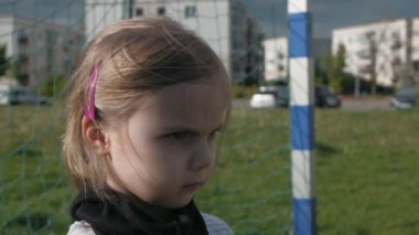 Siyah koruyucu maskeli tehditkar bakışlı bir kız futbol kalesinde duruyor. Sert bakışlı bir kaleci. Yavaş çekim
