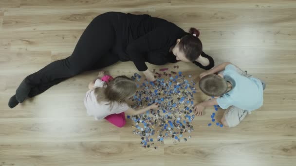 Kinderen Met Moeder Maken Een Puzzel Thuis Vloer Bovenaanzicht Slow — Stockvideo