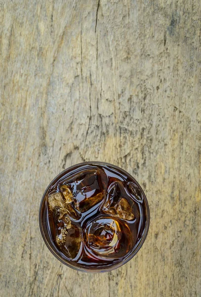 Cola in vetro con ghiaccio vista dall'alto su pavimento in legno . — Foto Stock