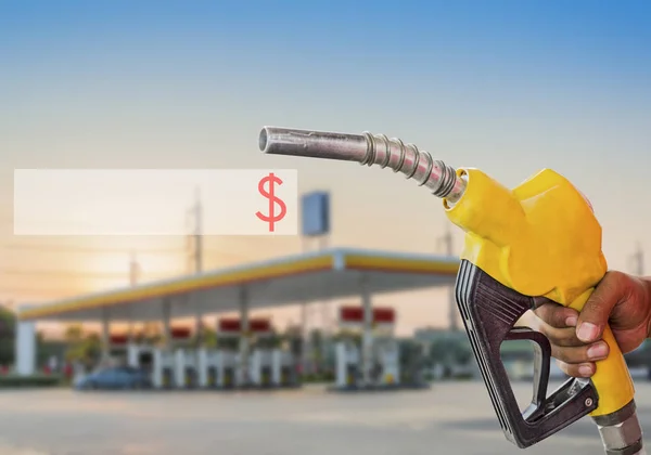 Holding a fuel nozzle against with gas station blurred backgroun — Stock Photo, Image