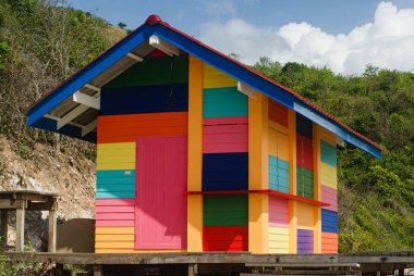 Yeşil tepenin arkasında çok renkli ahşap bir ev..