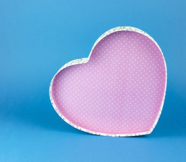 Pink heart-shaped box with white dots on a blue background.