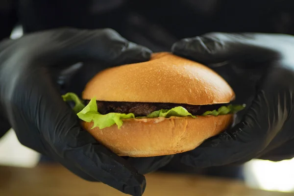 Elinde pirzola ve yeşil salata olan bir hamburger.