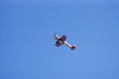 Old red-white helical airplane in the blue sky.