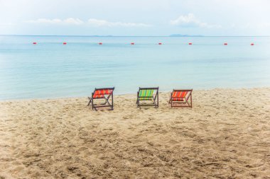 Three beach loungers on yellow sand 